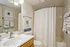 Elegant bathroom featuring modern sink, chic wall art, and a stylish shower with a patterned curtain.