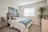 Bright and inviting bedroom with modern art, plush bedding, and warm natural light.