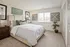 Bright and cozy bedroom with elegant decor, featuring a plush bed, stylish artwork, and natural light streaming through the window.