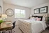 Elegant bedroom with a plush tufted bed, cozy pillows, and natural light streaming through large windows. Includes a stylish wooden desk and artistic wall decor, creating a serene and inviting atmosphere.