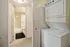 Bright laundry area with a stacked washer-dryer next to a modern bathroom featuring a sleek tub and elegant decor.