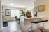 Bright and modern dining area with elegant decor, featuring a stylish breakfast bar and a view of lush greenery through large windows.