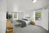 Elegant master bedroom with abundant natural light, featuring a cozy bed, modern decor, and serene outdoor views through large windows.