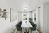 Elegant dining room with a sleek marble table, green velvet chairs, and large windows inviting natural light.