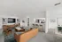 Modern apartment living room with cozy seating, stylish decor, and a breakfast bar leading to a sleek kitchen and dining area.