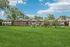 Charming two-story brick apartment complex surrounded by lush green lawns and mature trees, offering a serene living environment.
