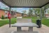 Charming outdoor space with a modern grill under a pergola, surrounded by lush green lawns and brick apartments.
