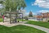 Charming outdoor area with a modern BBQ setup and seating, surrounded by lush greenery and a sparkling pool, perfect for relaxation and gatherings.