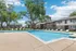 Inviting apartment complex with a pristine outdoor pool, surrounded by lush greenery and stylish sun loungers, offering a perfect blend of relaxation and scenic beauty.