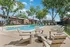 Inviting outdoor pool area surrounded by lush trees and modern apartment buildings, featuring comfortable lounge chairs and a serene ambiance.