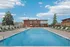 Inviting outdoor pool area with comfortable lounge chairs and a charming red-brick building set against a clear blue sky.