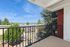 Inviting apartment balcony with a scenic view of lush greenery and cityscape under a bright blue sky.