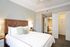 Elegant bedroom with plush bedding, stylish leather headboard, and en-suite modern bathroom.