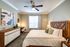 Elegant bedroom with a modern aesthetic, featuring a plush bed, stylish dresser, and chic workspace under natural light.