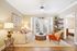 Elegant living room with cozy beige sofa, stylish wood accents, and natural light from large windows creating a warm, inviting space.