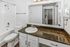 Elegant bathroom featuring modern fixtures, a spacious granite countertop, and a large mirror, offering a perfect blend of style and functionality.