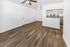 Bright, modern living area with elegant wood flooring, ceiling fan, and open-plan kitchen featuring stainless steel appliances.