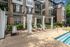 Elegant apartment complex with a serene poolside area, featuring stylish lounge chairs and a modern pergola under sunny skies.