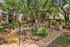 Charming apartment complex courtyard with lush greenery, cozy seating areas, and inviting pathways under a canopy of mature trees.
