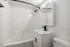 Modern bathroom featuring sleek white subway tiles, mirrored cabinet, and elegant black fixtures.