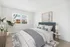 Bright, inviting bedroom with a plush navy headboard, modern decor, and ample natural light from large windows.