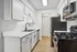 Modern kitchen with sleek white cabinets, stainless steel appliances, and elegant wood flooring, showcasing a minimalist and functional design.