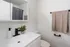 Modern bathroom with elegant white fixtures, a sleek vanity with a black faucet, and stylish decor plants for a fresh ambiance.