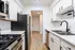 Modern kitchen with sleek stainless steel appliances, crisp white cabinetry, and elegant black hardware, featuring a spacious and bright layout.