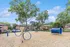 Inviting playground area with vibrant blue play structures, lush trees, and charming brick residential buildings in the background.