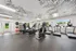 Modern fitness center with state-of-the-art treadmills, exercise bikes, and vibrant wall art, flooded with natural light from large windows.