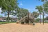 Inviting outdoor playground in a lush apartment community, surrounded by towering trees and well-maintained green spaces.