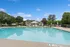 Inviting apartment complex with a sparkling outdoor pool, surrounded by lush greenery and comfortable lounge areas.