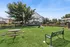 Charming apartment community with spacious green lawn, picnic tables, and modern play area for outdoor enjoyment.
