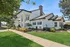 Elegant colonial-style building with grand white pillars, manicured landscaping, and vibrant green lawn under a clear blue sky.