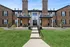 Charming brick apartment complex with elegant balconies and neatly landscaped entrance.