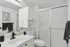 Sleek modern bathroom with a spacious shower, elegant white cabinetry, and stylish black fixtures.