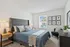 Elegant bedroom featuring a plush bed with stylish bedding, modern nightstands, artwork, and ample natural light through a bright window.