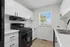 Bright modern kitchen with sleek black appliances, white cabinetry, and a scenic window view.