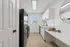 Bright and modern kitchen featuring sleek black appliances, white cabinetry, and a stylish breakfast counter with natural light flooding through the window.