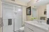 Elegant bathroom with a modern shower, granite countertop, and chic decor accents.