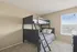 Bright bedroom with elegant dark wood bunk bed, plush carpeting, and ample natural light from a large window.