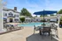 Elegant apartment community with a pristine swimming pool, stylish lounge chairs, and charming white architecture creating a perfect relaxation spot.