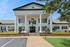 Elegant white colonial-style building with grand columns and manicured gardens, perfect for your next upscale apartment living.
