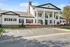 Elegant colonial-style building with grand white columns, beautifully manicured landscaping, and spacious parking area.