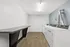 Modern laundry room with sleek white machines, wooden flooring, and ample folding space in a contemporary apartment.