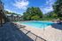 Inviting outdoor pool area with stylish lounge chairs and lush greenery, perfect for relaxation and leisure.