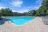 Inviting outdoor swimming pool area with sun loungers, lush green surroundings, and elegant residential buildings in the background.