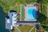 Aerial view of a luxurious property featuring a large swimming pool, well-manicured gardens, and a modern clubhouse by the water.