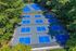 Aerial view of a vibrant tennis court complex surrounded by lush greenery, offering multiple blue courts for an invigorating sports experience.