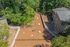 Spacious outdoor area featuring a landscaped yard with large rocks, surrounded by lush greenery and adjacent to modern apartment buildings.